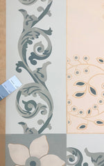 Load image into Gallery viewer, A close up of Graves Circles and Scrolls Floorcloth #3 with a chip of the room wall color placed against the floorcloth.