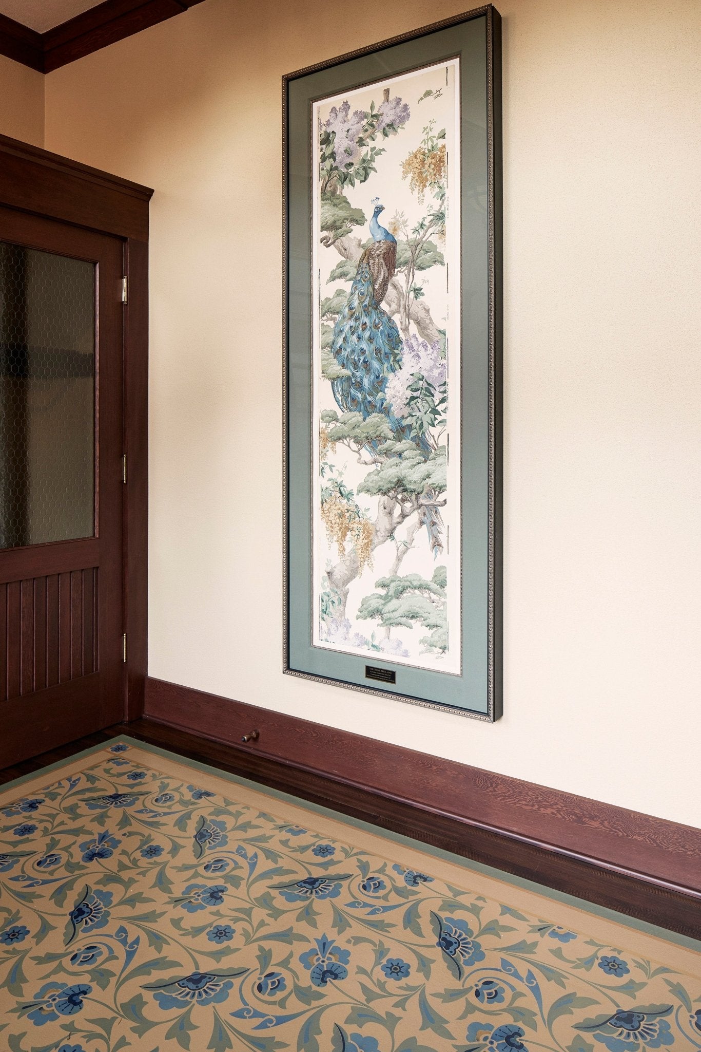 In-situ image of a shaped floorcloth, made to perfectly fit this space. The design is an all over floral pattern by Christopher Dresser. The Peacock is an original wallpaper panel c.1910 from Arthur Sanderson & Sons. Photo by Sally Painter.