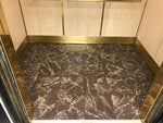 Load image into Gallery viewer, In-situ image of this floorcloth at the base of an elevator car.  The pattern emulates Emperador Dark marble tile. 
