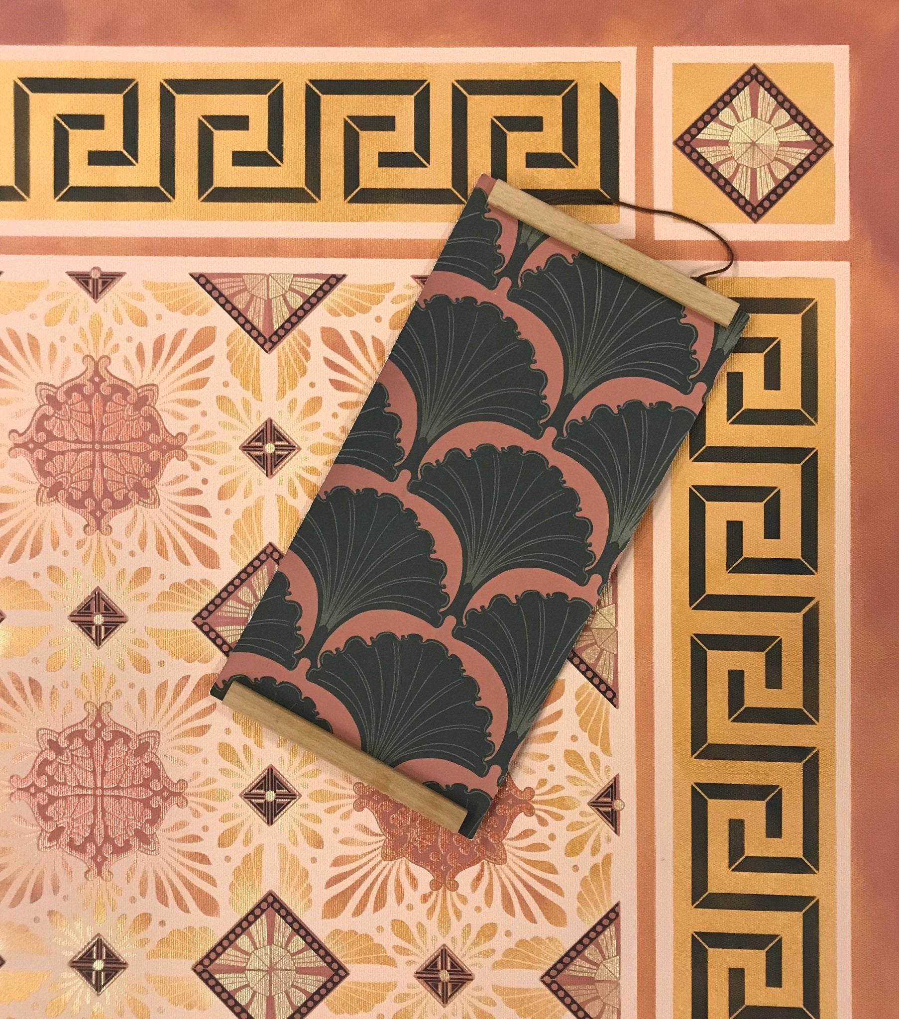 A close up of the corner of this floorcloth with a sample of Lonesome Pictopia's Chanterelles wallpaper, the palette inspiration for this floorcloth, displayed on top.
