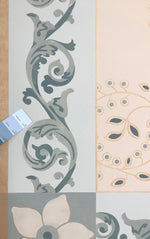 Load image into Gallery viewer, A close up of Graves Circles and Scrolls Floorcloth #3 with a chip of the room wall color placed against the floorcloth.
