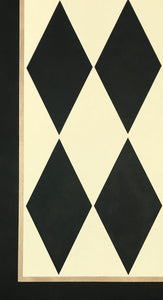 A close up of this harlequin patterned floorcloth in a soft yellow-white and charcoal colorway.