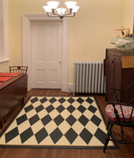Load image into Gallery viewer, In-situ image of this 5&#39;3&quot; x 6&#39; harlequin patterned floorcloth in a soft yellow-white and charcoal colorway.

