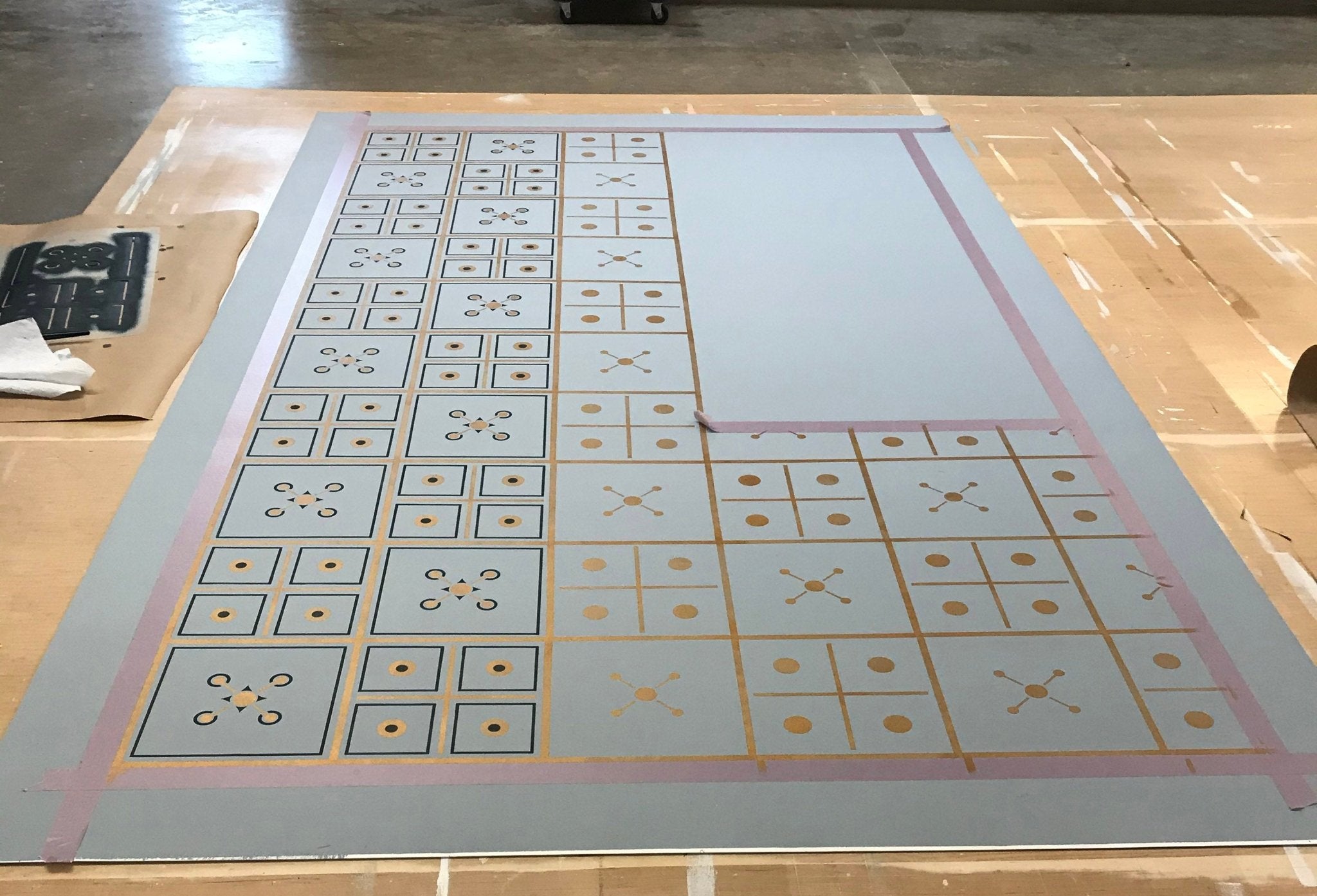 Image of this floorcloth in production in the middle of the second of three stencil passes.
